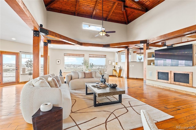 living room with ceiling fan, beam ceiling, high vaulted ceiling, wooden ceiling, and light wood-type flooring