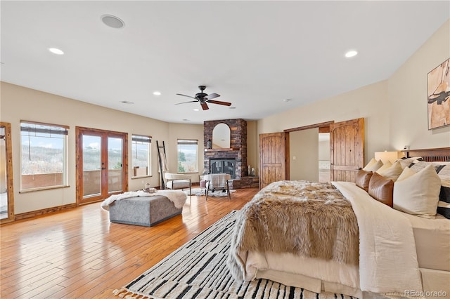 bedroom with french doors, light hardwood / wood-style flooring, access to outside, ceiling fan, and a fireplace