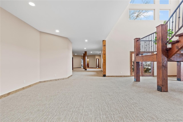 unfurnished living room with light colored carpet and a towering ceiling