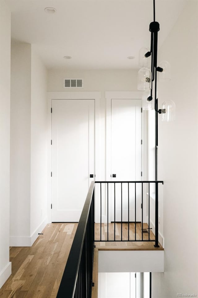 2753 Curtis St, Denver, CO 80205 - hallway with an upstairs landing, visible vents, baseboards, and light wood-style floors