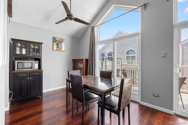 dining room with ceiling fan, dark hardwood / wood-style floors, high vaulted ceiling, and a textured ceiling