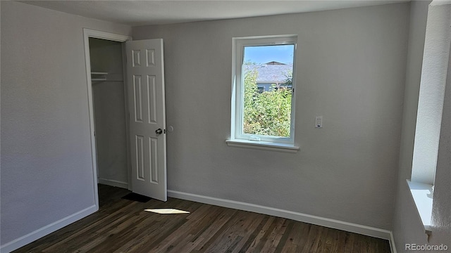 unfurnished bedroom with dark wood-type flooring and a closet