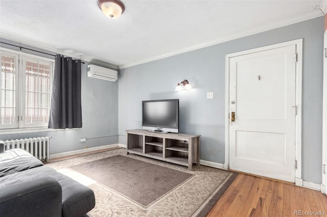 living room featuring baseboards, radiator, hardwood / wood-style flooring, crown molding, and an AC wall unit