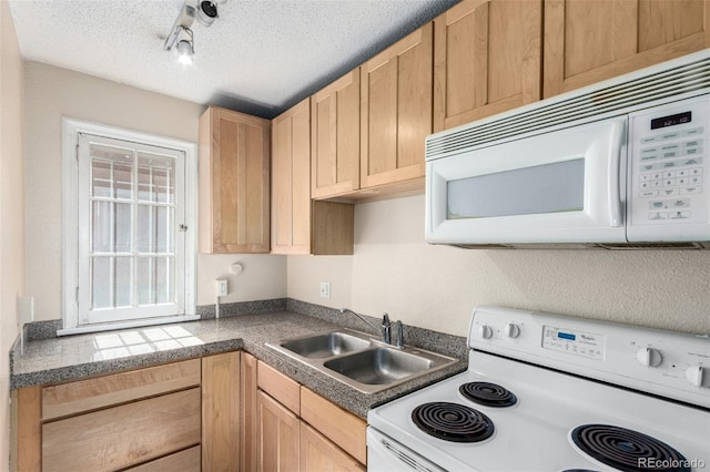 kitchen featuring light brown cabinetry, a sink, a textured ceiling, track lighting, and white appliances