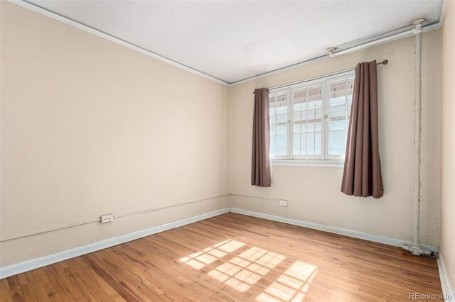 unfurnished room featuring hardwood / wood-style flooring, baseboards, and a textured ceiling