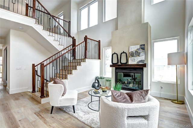 living room with plenty of natural light, light wood-type flooring, and a high ceiling