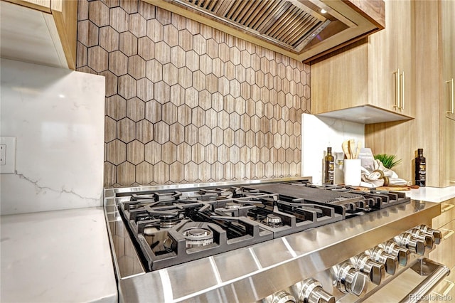 interior details featuring wall chimney range hood and light brown cabinets