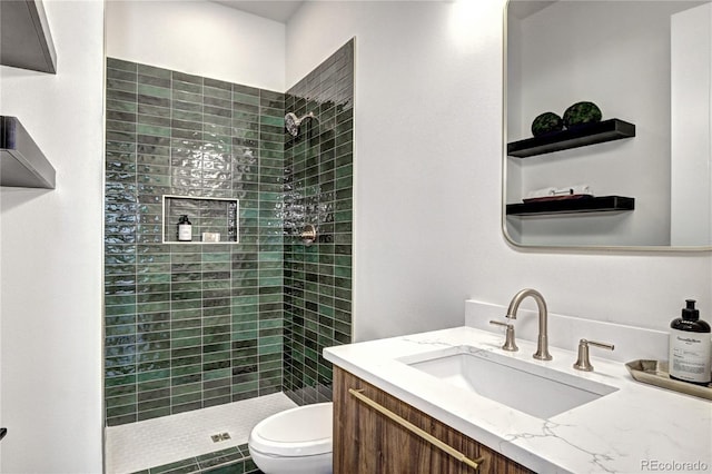 bathroom with toilet, vanity, and tiled shower