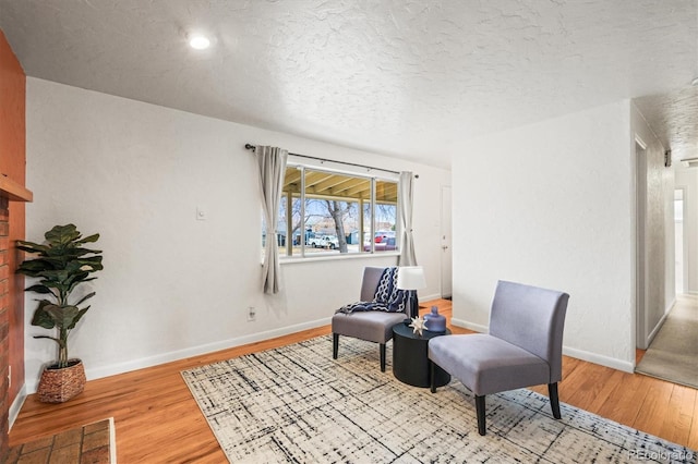 living area featuring light wood-type flooring, baseboards, visible vents, and a textured ceiling