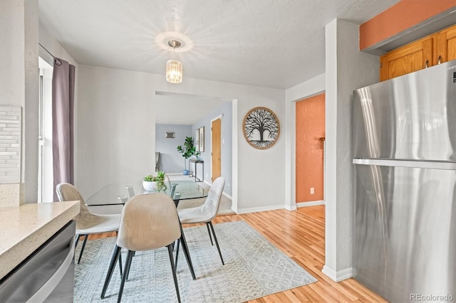 dining area with an inviting chandelier, light wood-style flooring, and baseboards