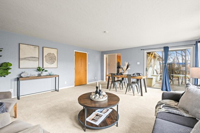 living area featuring light carpet, baseboards, and a textured ceiling