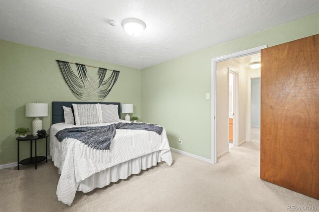 carpeted bedroom featuring a textured ceiling and baseboards