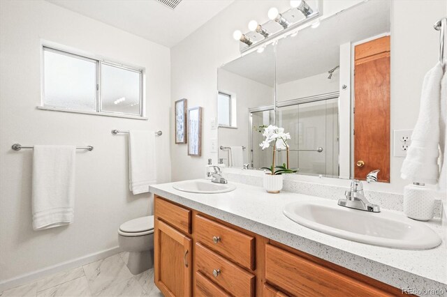 bathroom with double vanity, a shower stall, toilet, and a sink