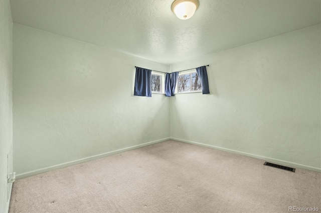 unfurnished room with carpet floors, visible vents, a textured ceiling, and baseboards