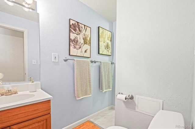 bathroom with baseboards, vanity, and toilet