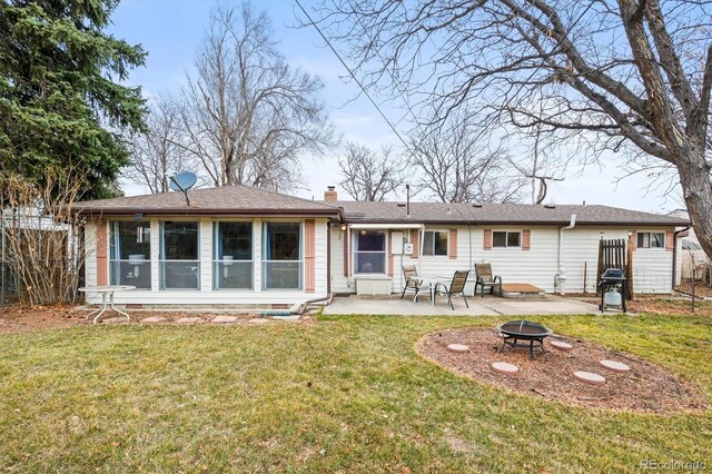 rear view of house featuring a patio, a chimney, a lawn, an outdoor fire pit, and fence