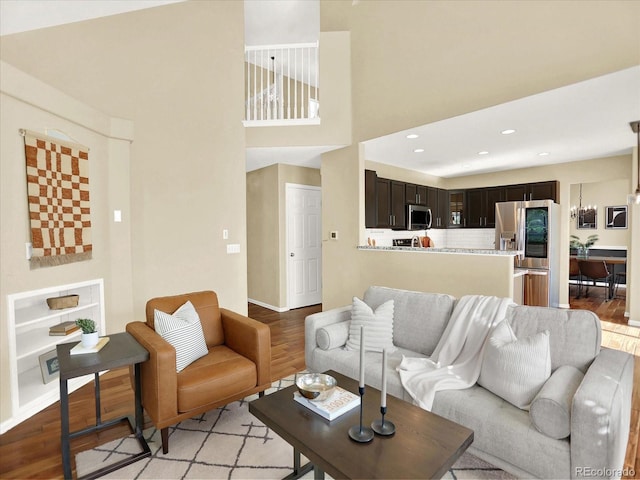 living area featuring light wood-style flooring, baseboards, recessed lighting, and a towering ceiling