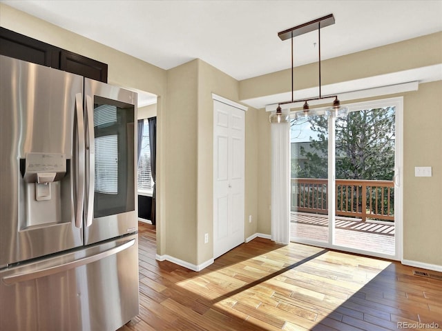 kitchen with stainless steel refrigerator with ice dispenser, hardwood / wood-style flooring, and baseboards