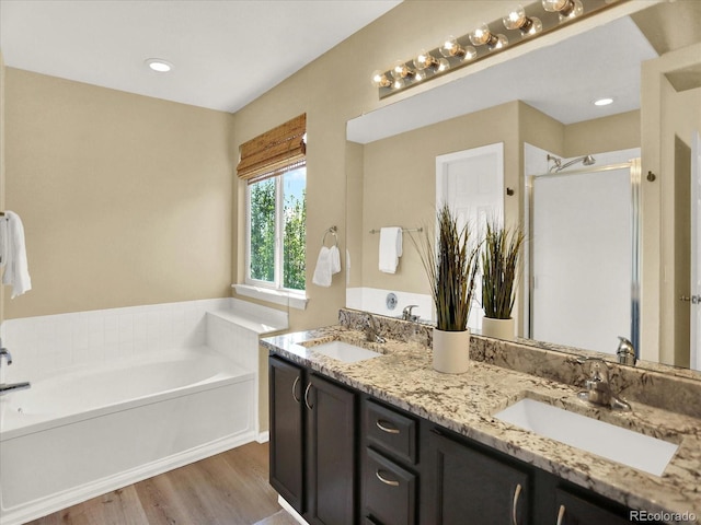 full bathroom with wood finished floors, a garden tub, double vanity, and a shower stall