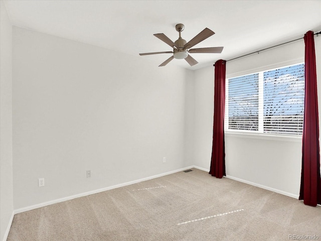 carpeted empty room with a ceiling fan and baseboards