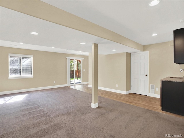 unfurnished living room featuring a sink, carpet, baseboards, and recessed lighting