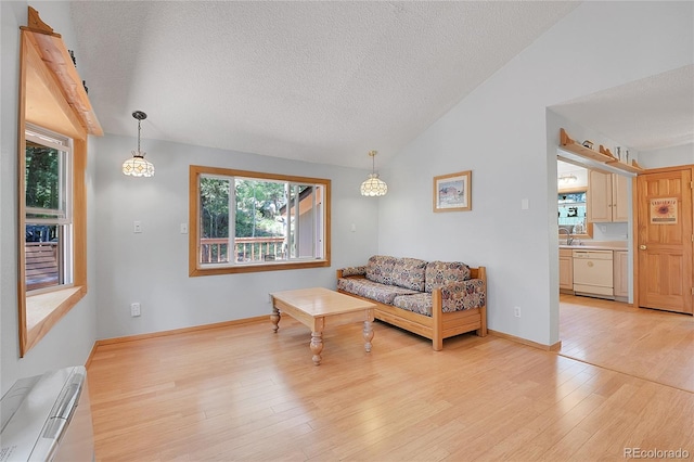 living room featuring vaulted ceiling, sink, a textured ceiling, and light hardwood / wood-style floors