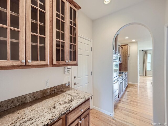 kitchen featuring light stone counters, oven, white oven, and light hardwood / wood-style floors