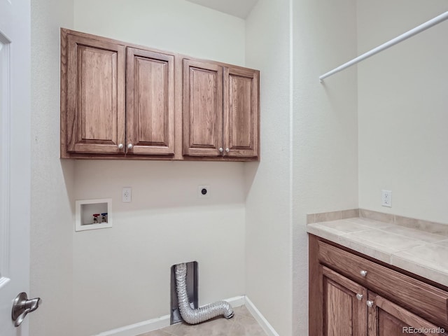 laundry room featuring hookup for a washing machine, light tile patterned flooring, hookup for an electric dryer, and cabinets