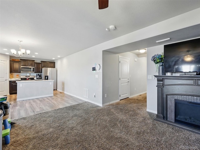unfurnished living room featuring a chandelier, baseboards, a glass covered fireplace, recessed lighting, and light carpet