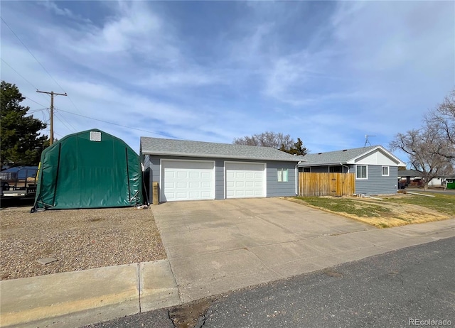 view of front of property with an outbuilding, a shingled roof, and fence