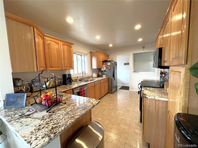 kitchen with a sink, stainless steel appliances, light stone counters, and a peninsula