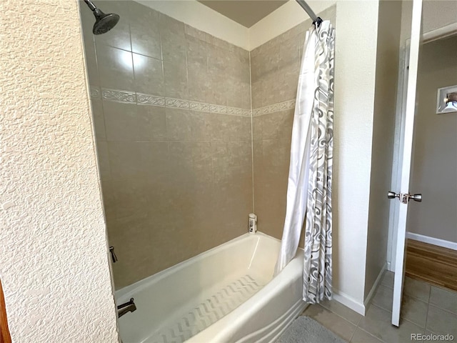 bathroom with baseboards, shower / bath combo with shower curtain, and tile patterned flooring