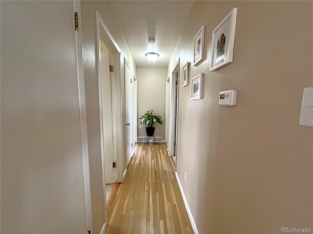 corridor with visible vents, baseboards, and light wood-style floors