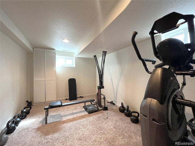 workout room featuring baseboards, a textured ceiling, and carpet