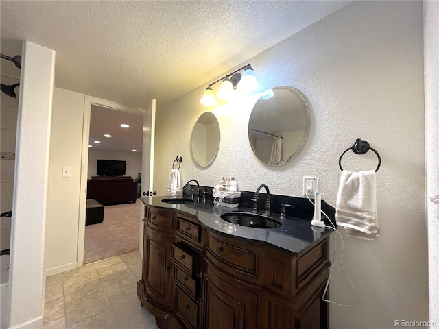 ensuite bathroom featuring a textured ceiling, double vanity, ensuite bathroom, and a sink