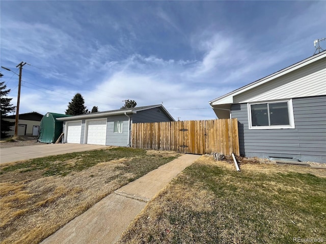 exterior space featuring a detached garage, an outbuilding, and fence