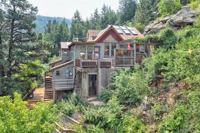 back of house featuring stairs and a wooded view