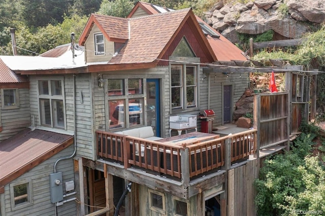 back of property with a wooden deck and roof with shingles