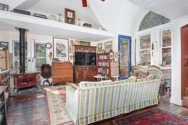 living area featuring a ceiling fan, hardwood / wood-style flooring, a wood stove, and vaulted ceiling