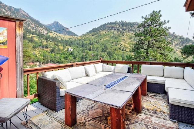 deck featuring an outdoor living space, a mountain view, and a forest view