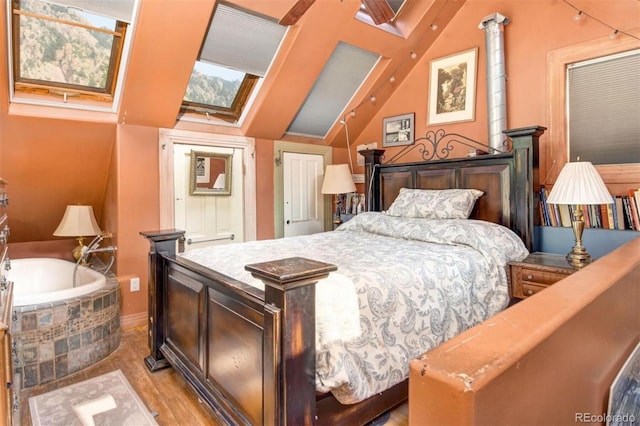 bedroom with baseboards, vaulted ceiling with skylight, and light wood finished floors