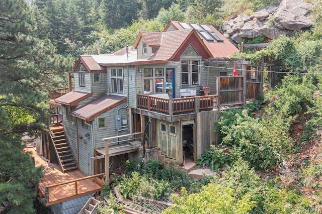 back of house featuring a deck, stairway, and a wooded view