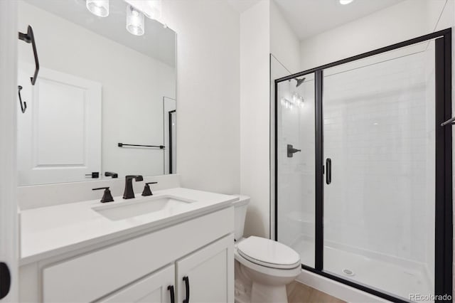 bathroom featuring vanity, toilet, and a shower with shower door