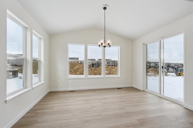 unfurnished dining area with a chandelier, plenty of natural light, light hardwood / wood-style flooring, and lofted ceiling