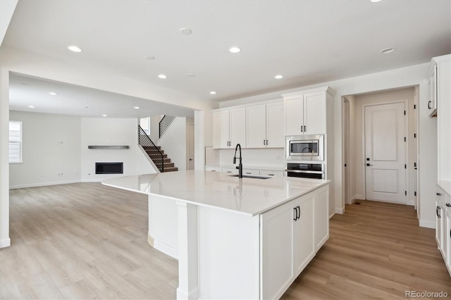 kitchen with white cabinets, an island with sink, stainless steel appliances, and sink