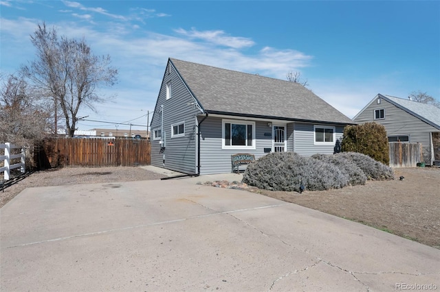 view of front of house with concrete driveway, fence, and roof with shingles