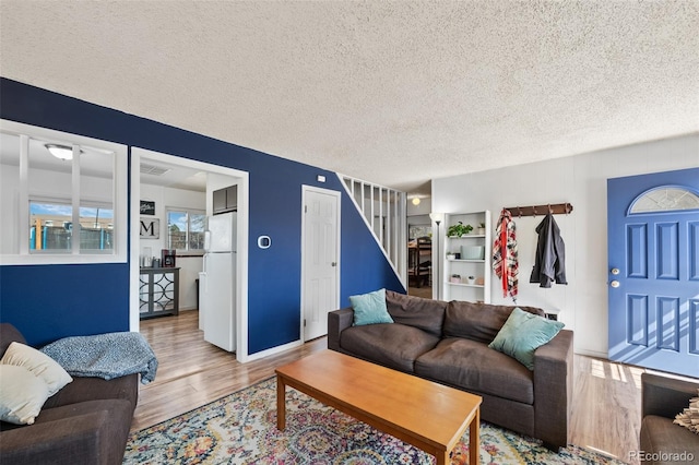 living area featuring wood finished floors, visible vents, and a textured ceiling