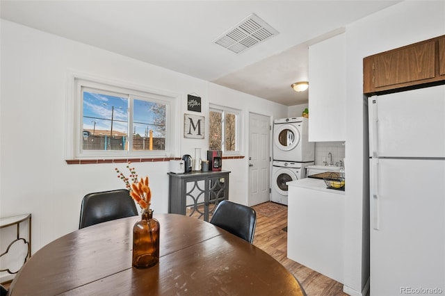 dining room featuring stacked washer / dryer, visible vents, and light wood-type flooring