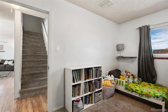 interior space featuring visible vents, a textured ceiling, and wood finished floors