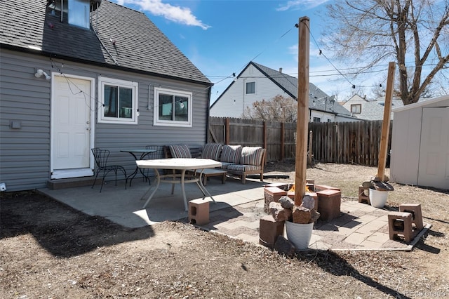 view of patio with a fire pit, a storage shed, a fenced backyard, and an outdoor structure